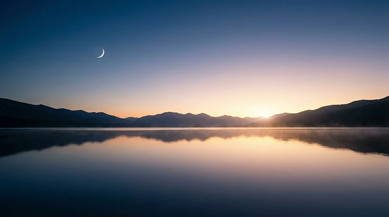 Stiller See bei Dämmerung mit Mondsichel und Bergsilhouetten - Symbol für innere Ruhe und sanfte Begleitung