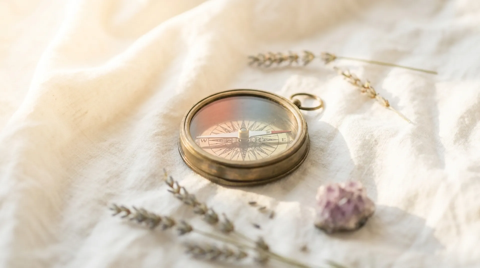 Messingkompass auf hellem Leinen mit Lavendel und Amethyst